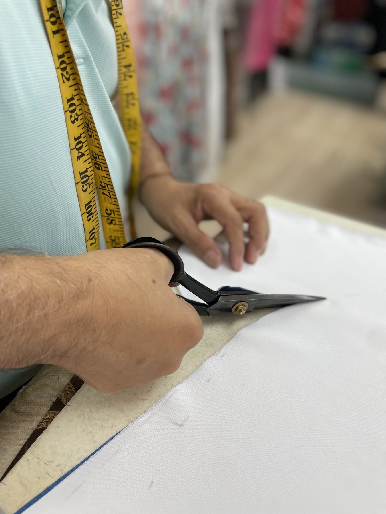 Master tailor hand-cutting fabric with shears at GM Custom Clothier, a bespoke tailor in Sugar Land, TX